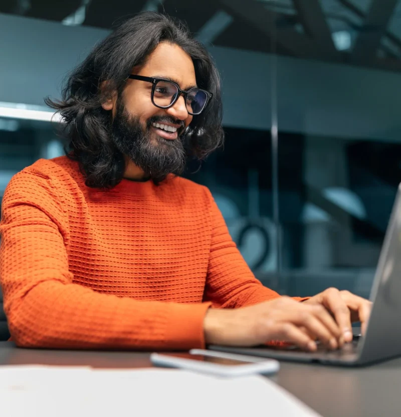 A developer smiling while working at a laptop